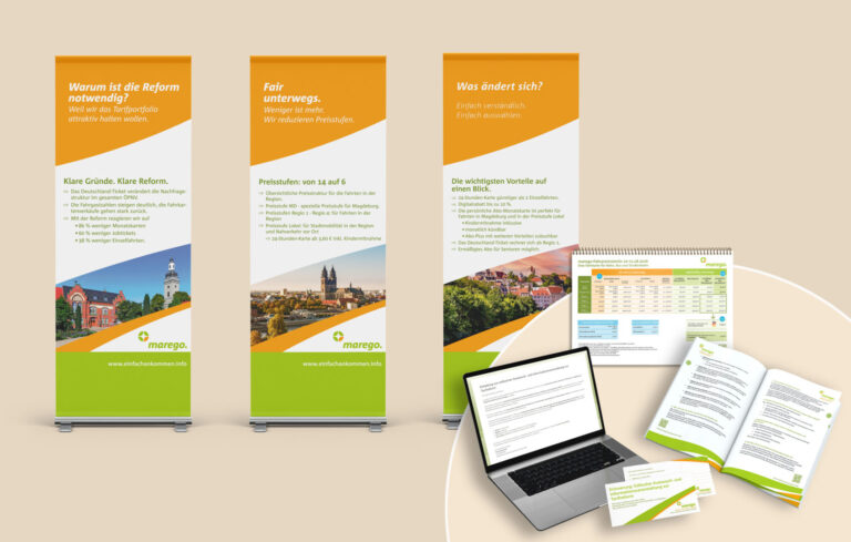 Three tall Marego promotional banners with orange tops, diagonal white sections, green bottom, and city photos at the base showing a marketing display.